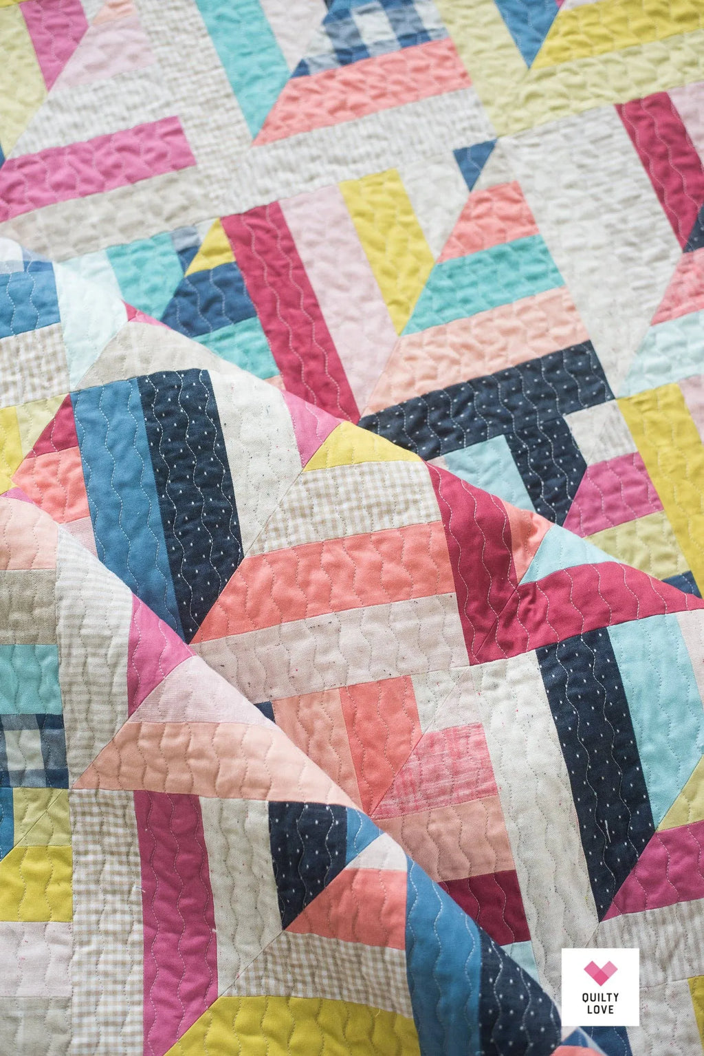 Colorful quilt with geometric pattern on a white background Lucky Log Cabin by Quilty Love