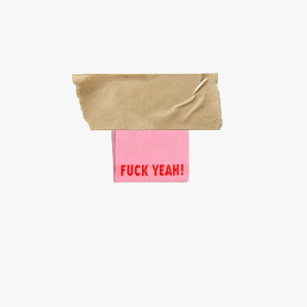 Fuck Yeah! woven labels by KATM in bold red on pink background.