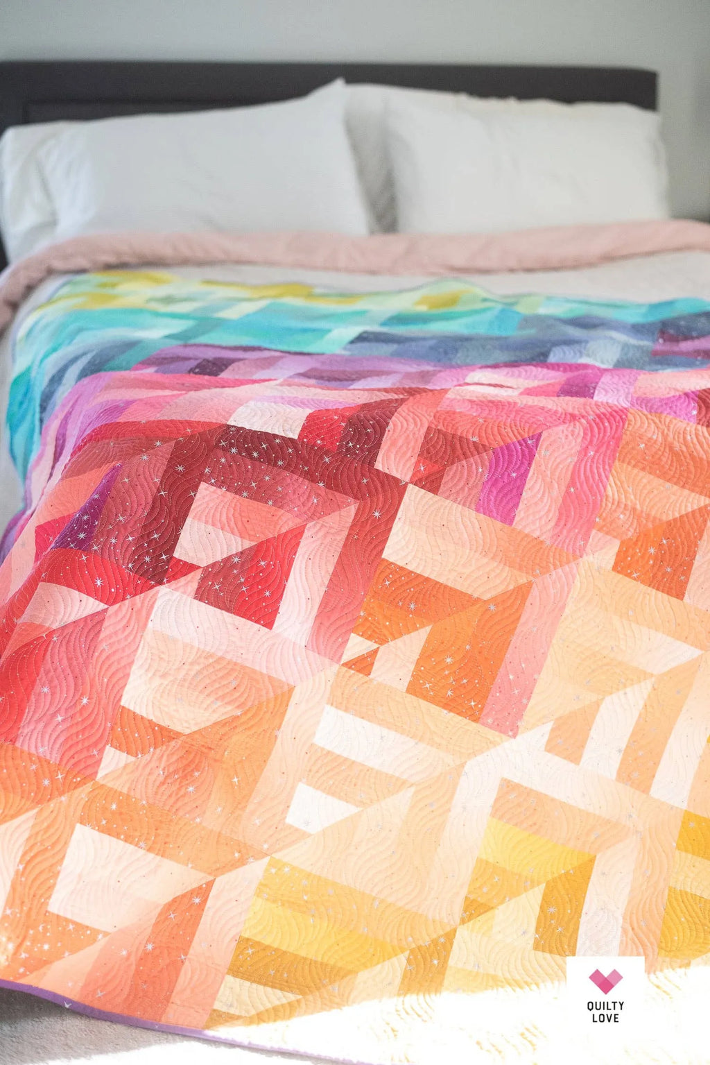 Colorful quilt with geometric pattern on a bed Lucky Log Cabin by Quilty Love