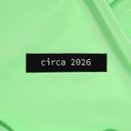 Text 'circa 2026' on a green fabric background KATM Labels