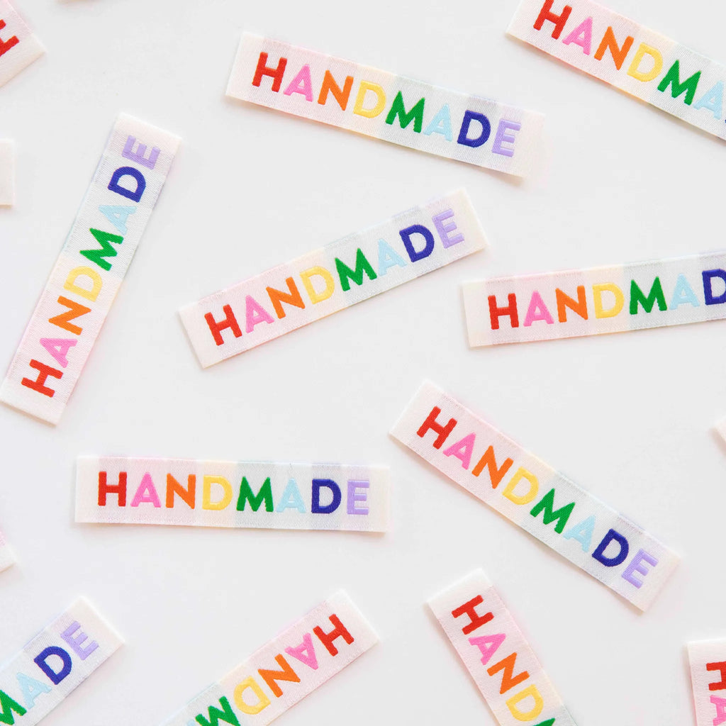 Colorful 'HANDMADE' stickers scattered on a white background