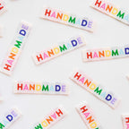 Colorful 'HANDMADE' stickers scattered on a white background