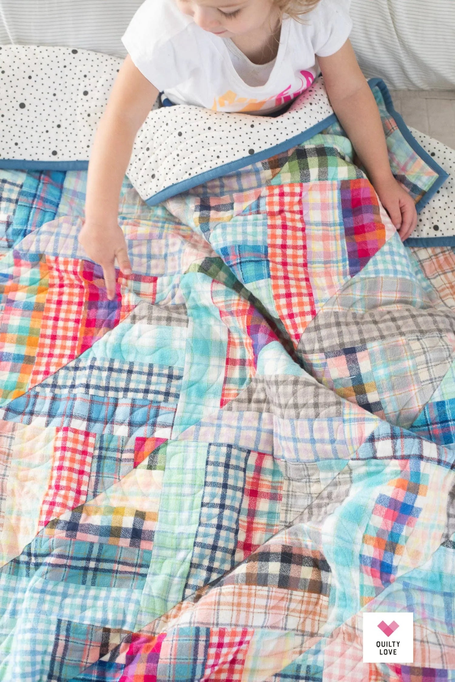 Colorful patchwork quilt with a visible brand logo. Lucky Log Cabin by Quilty Love