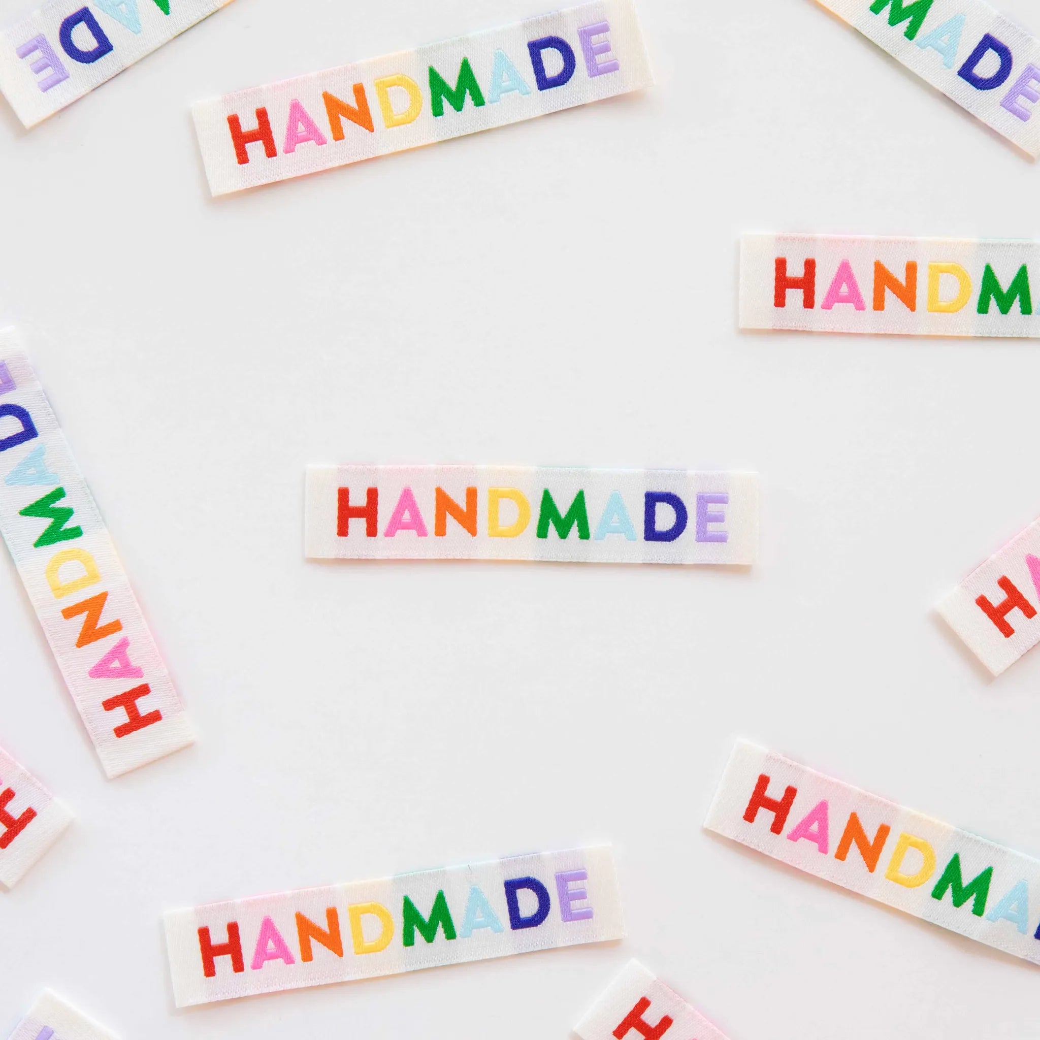 Colorful 'HANDMADE' text on small rectangular stickers scattered on a white background