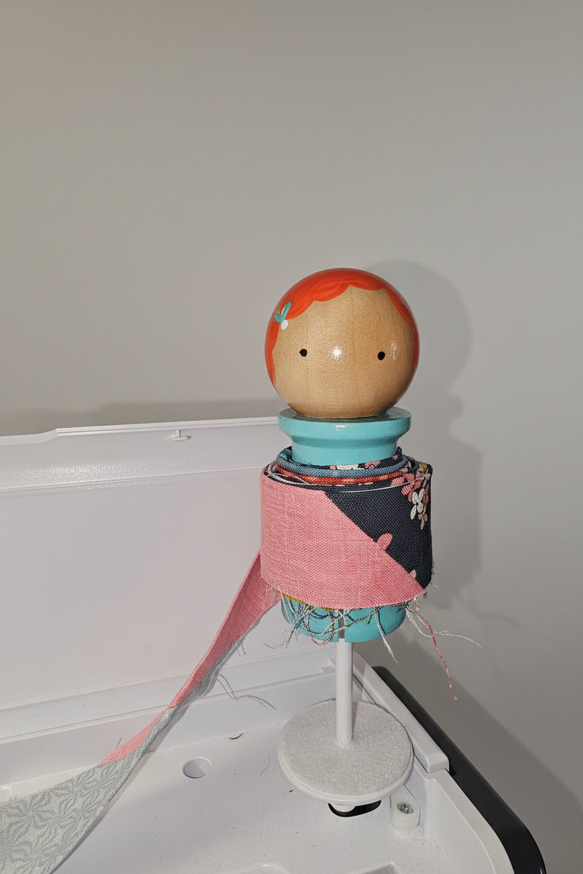 Binding Babies Annie on a sewing machine spool.