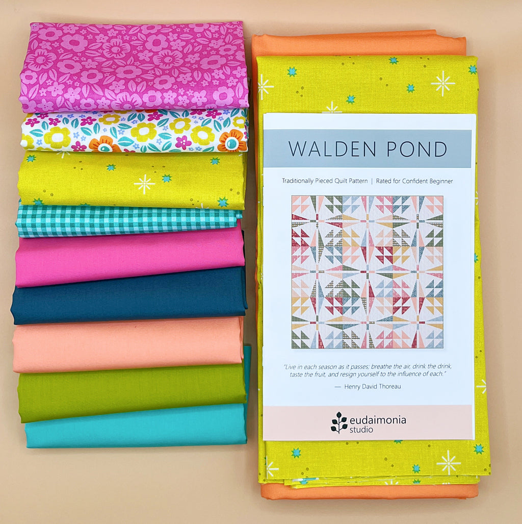 Stack of colorful fabric bundles included with a quilt pattern book titled 'Walden Pond' on a beige background.