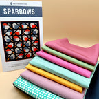 Sparrows quilt kit with pattern booklet and a stack of folded solid and grid-print fabrics in pink, green, mint, yellow and navy