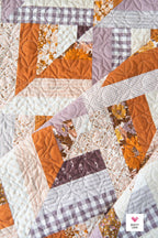 Quilt with patchwork design featuring various colors and patterns. Lucky Log Cabin by Quilty Love