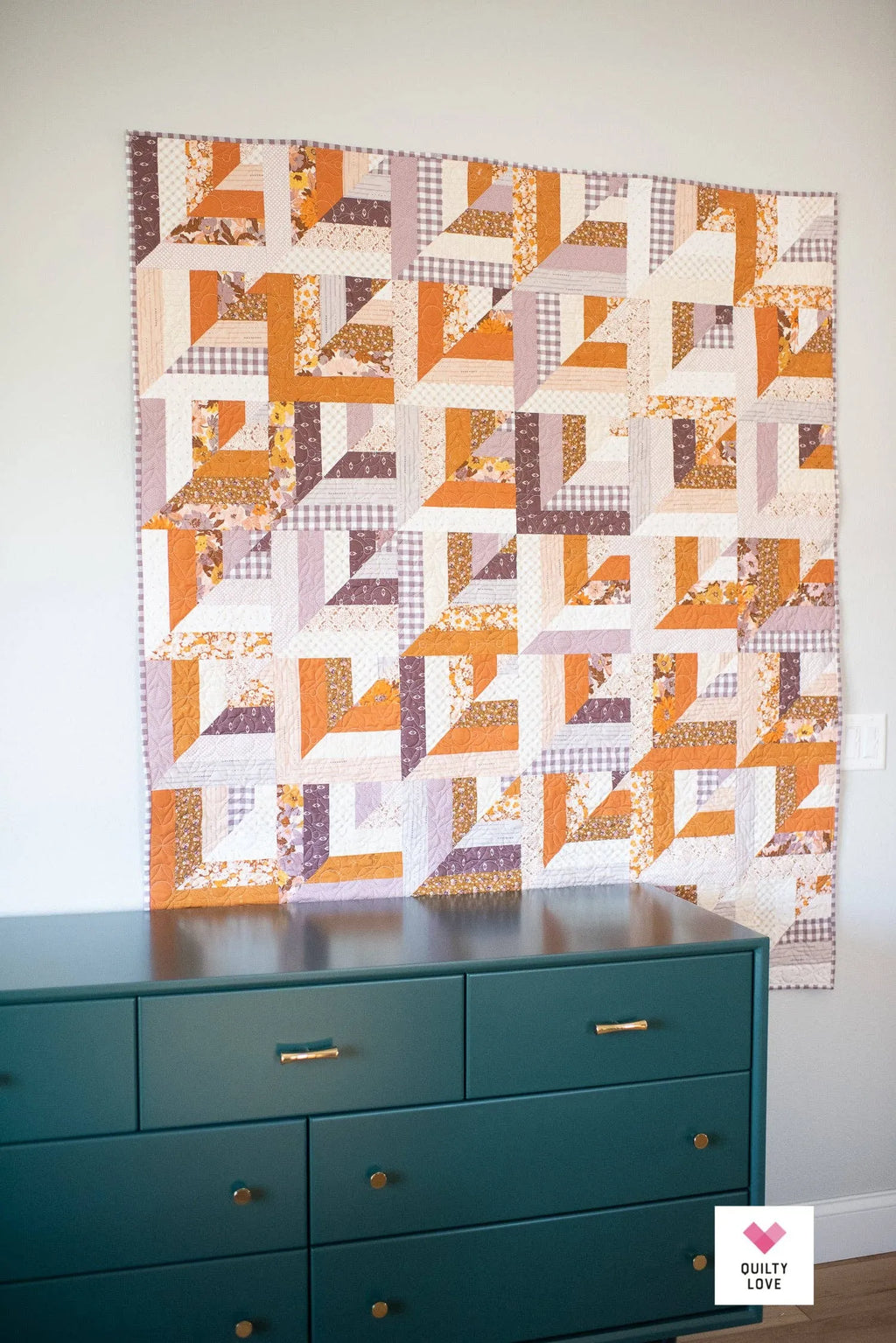 Quilt with geometric pattern hanging above a teal dresser Lucky Log Cabin by Quilty Love