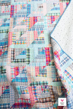 Colorful patchwork quilt with geometric patterns on a textured surface Lucky Log Cabin by Quilty Love