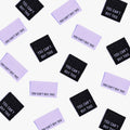 You Can't Buy This metallic woven labels scattered in black and purple.