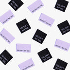 You Can't Buy This metallic woven labels scattered in black and purple.