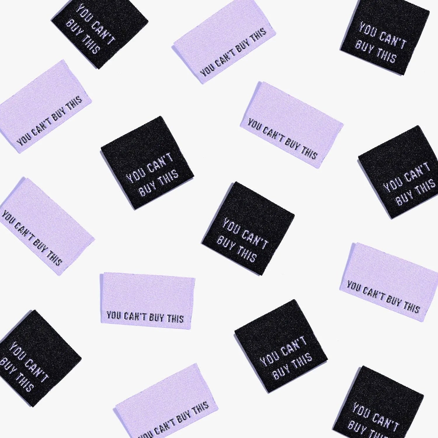 You Can't Buy This metallic woven labels scattered in black and purple.