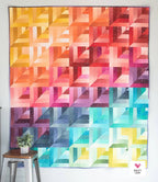 Colorful geometric quilt with a geometric pattern on a white wall. 2 1/2" strip friendly quilt pattern